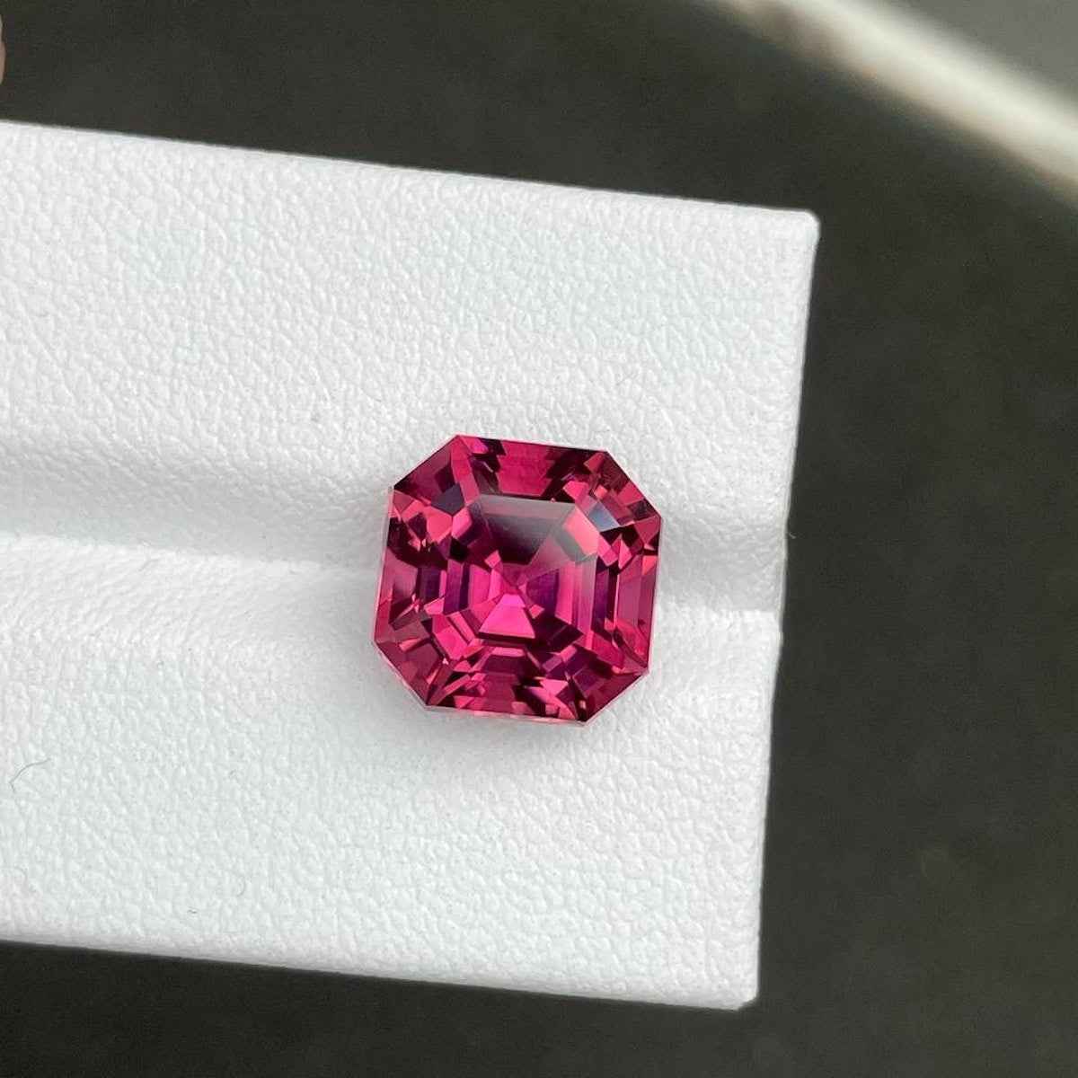 La Tourmaline Rose · 6,79 ct de Bonnot Paris est exposée sur un fond blanc texturé, mettant en valeur sa forme carrée rose vif et sa surface facettée qui reflète brillamment la lumière, améliorant sa clarté et sa teinte vibrante.