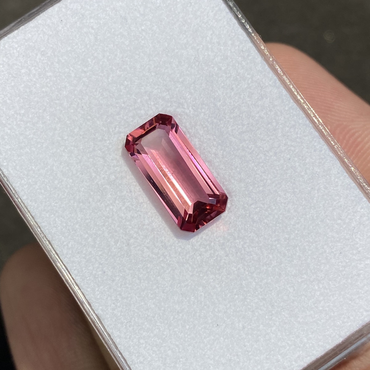 La Tourmaline Rose de 3,95 carats de Bonnot Paris est présentée sur un fond blanc dans une main. Cette pierre rose rectangulaire présente des bords biseautés et une surface brillante et translucide qui met en valeur sa couleur vive.