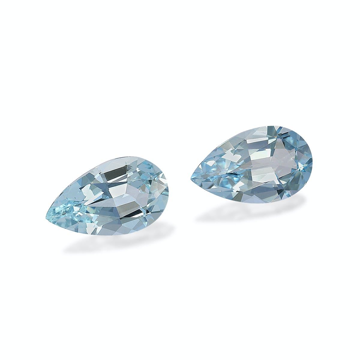 Deux pierres précieuses bleues en forme de poire de Bonnot Paris, une Aigue-Marine de 2,72 carats, reposent sur une surface claire. Facettées à la perfection, elles reflètent la lumière avec élégance et sophistication, leurs extrémités pointues se faisant face telles des bijoux raffinés.