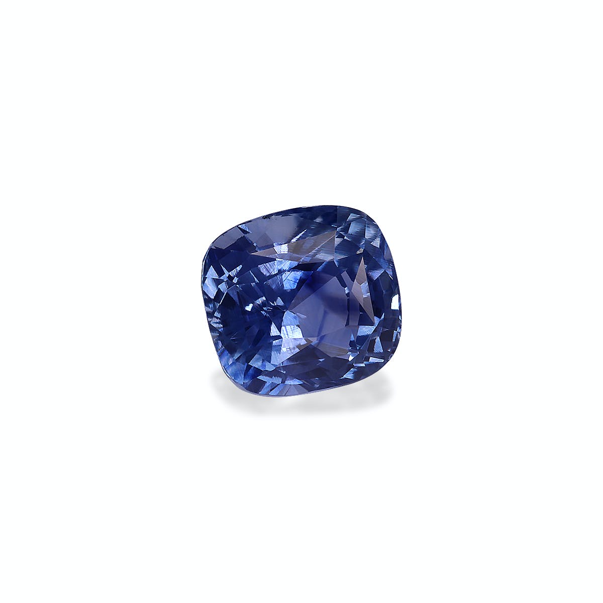 Le Saphir Bleu · 3,13 carats de Bonnot Paris est orné d'un saphir bleu taille coussin à la surface facettée, reflétant magnifiquement la lumière. Cette pierre d'un bleu profond présente des reflets plus clairs sur un fond gris clair.