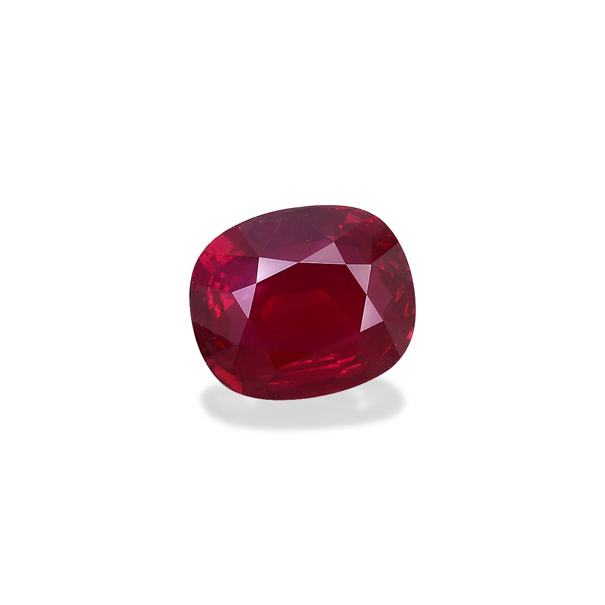 Le Rubis du Mozambique de Bonnot Paris, un rubis taille coussin rouge vif de 5 carats, présente une surface facettée qui reflète brillamment la lumière, posée sur un fond blanc uni pour mettre en valeur sa couleur profonde et sa clarté.