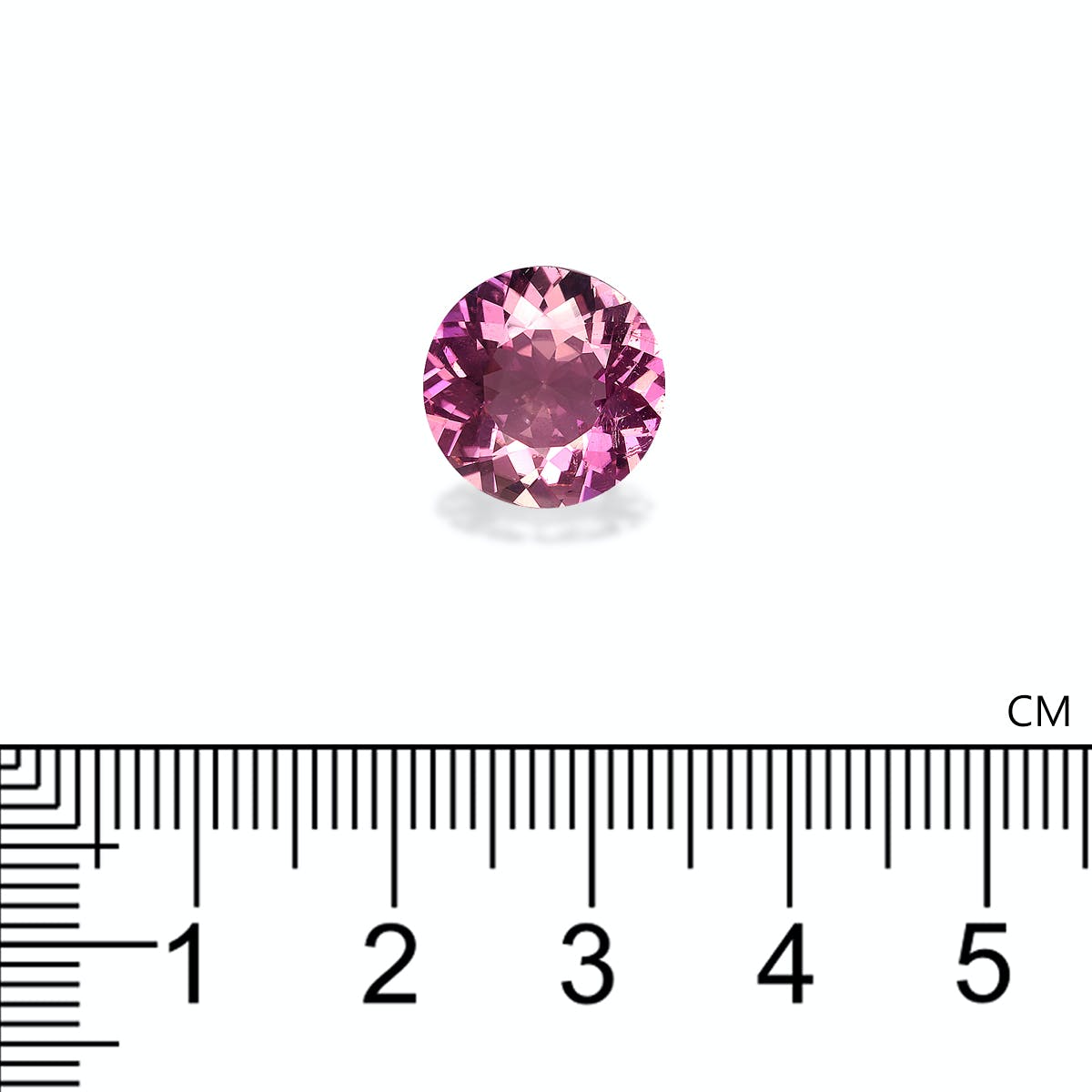 Une tourmaline cuprifère de 5,22 carats de Bonnot Paris est sertie sur une surface blanche, à côté d'une règle graduée en centimètres. Cette pierre rose ronde mesure environ 1,5 cm de diamètre et reflète magnifiquement la lumière avec un effet scintillant. La règle est placée horizontalement sous la pierre.