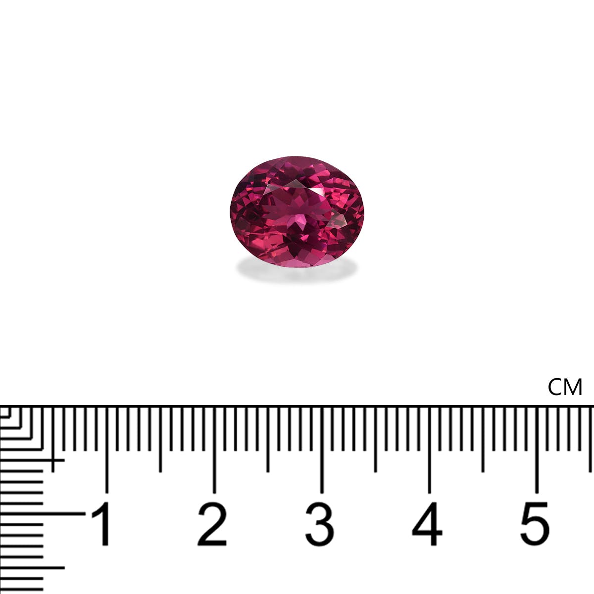 Une tourmaline rose ovale de 5,88 carats de Bonnot Paris est présentée au-dessus d'une règle graduée, mesurant environ 0,5 cm de large. Sa surface facettée reflète des nuances roses variées sur un fond blanc uni.