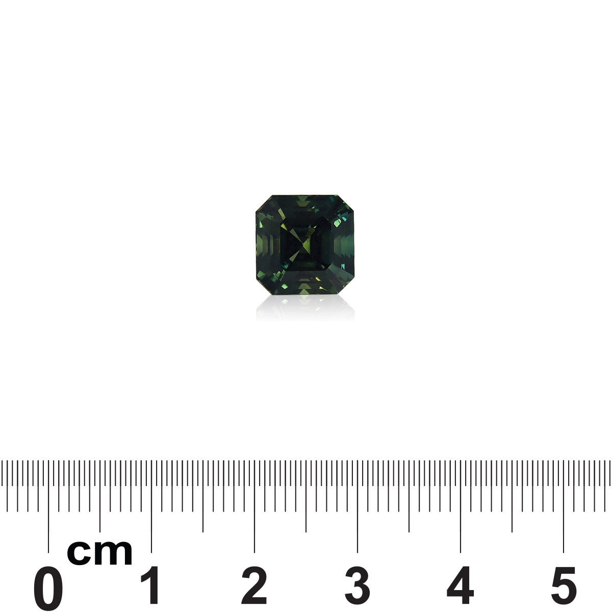 Au centre de l'image se trouve un petit saphir vert taille carrée de Bonnot Paris, entouré d'un fond blanc. Une règle en dessous indique qu'il mesure environ 1,1 cm de large et pèse 6,53 carats.