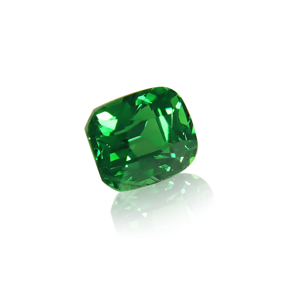 La Grenat Tsavorite Bonnot Paris, une pierre précieuse taille coussin d'un vert vibrant de 1,55 ct, est inclinée sur un fond blanc pour mettre en valeur sa surface réfléchissante.