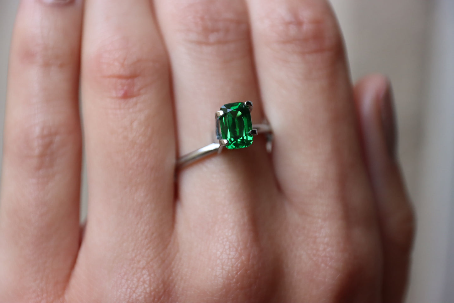Une main portant une bague Bonnot Paris Grenat Tsavorite, comportant une pierre précieuse rectangulaire vert émeraude de 1,53 ct dans un sertissage à griffes simple, mettant en valeur sa couleur vibrante.