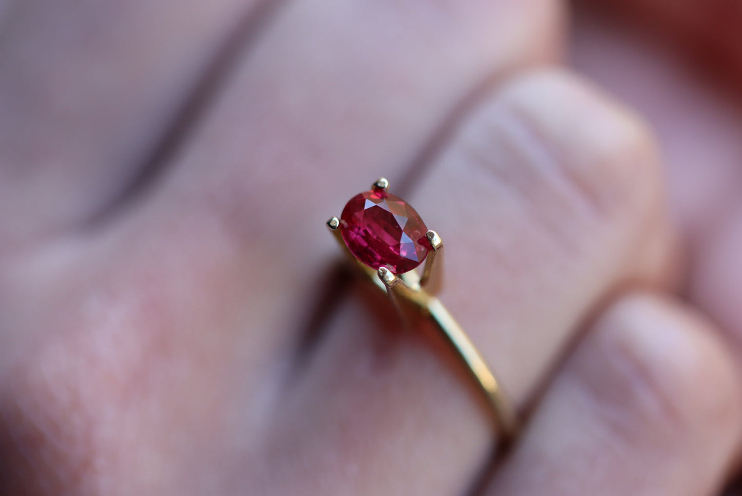 Gros plan d'une main portant la bague en or « Rubis du Mozambique · 1,52 ct » de Bonnot Paris, ornée d'une pierre rouge ovale. L'arrière-plan flou met en valeur la couleur vive et l'éclat de la pierre.