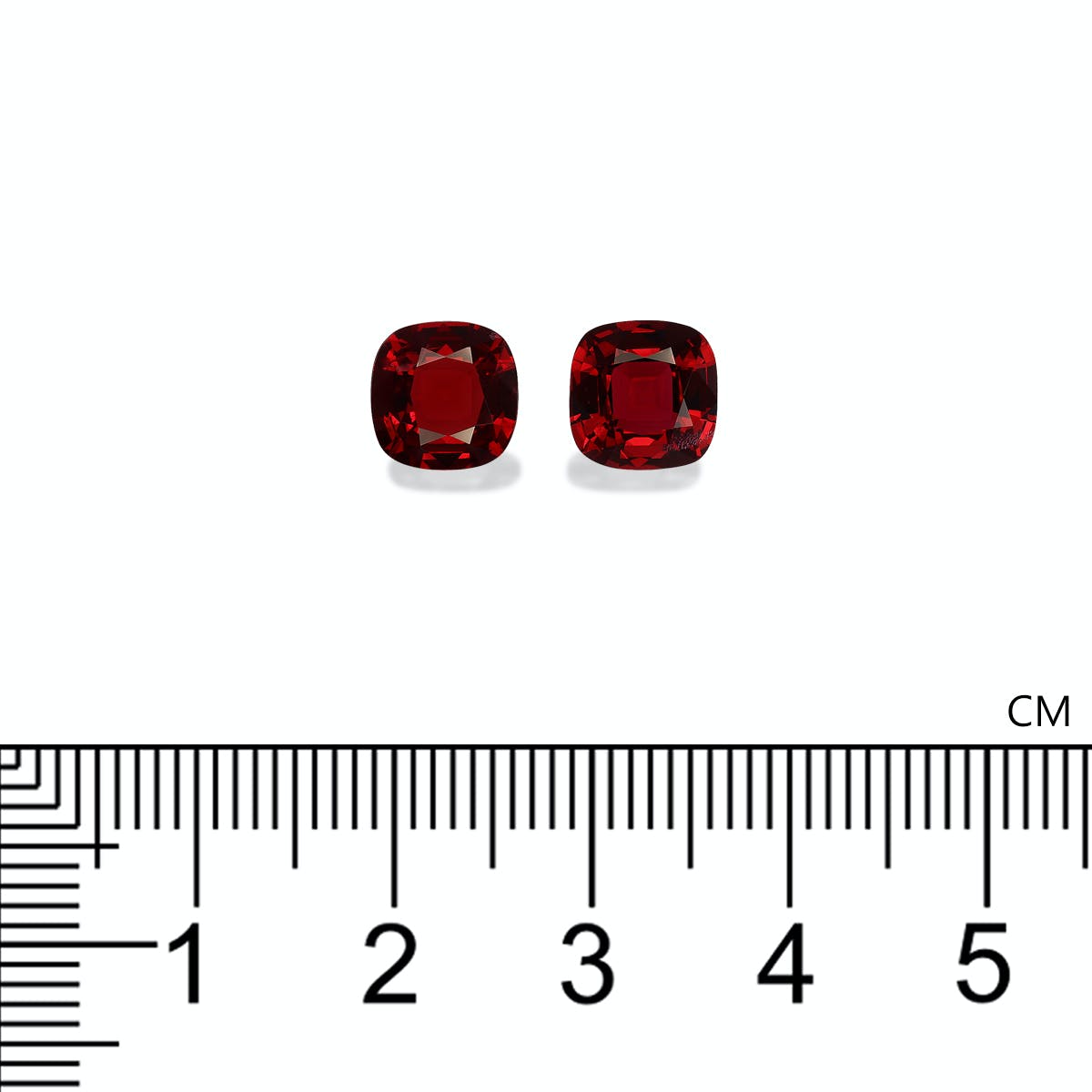 Deux pierres précieuses Spinelle Rouge taille carrée de Bonnot Paris, mesurant chacune environ un centimètre de diamètre, sont placées au-dessus d'une règle centimétrique pour l'échelle sur un fond blanc.