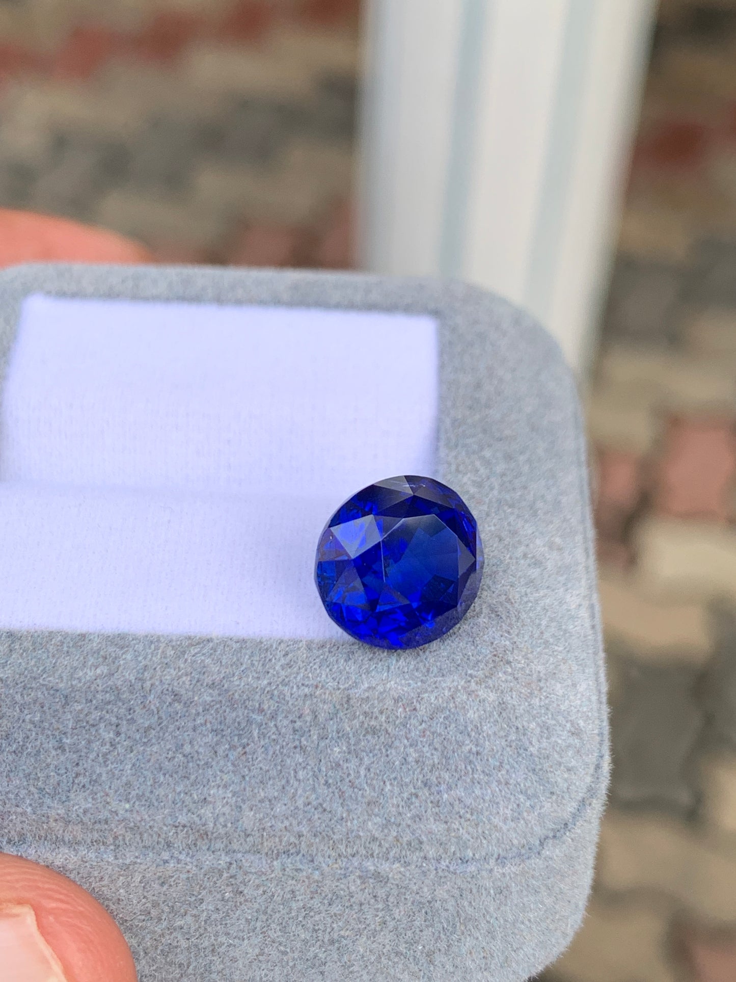 Un gros plan met en valeur le bleu éclatant du Saphir Bleu Bonnot Paris de 8,03 ct, posé sur un écrin gris clair. L'arrière-plan flou met en valeur sa surface facettée exquise et sa couleur éclatante.