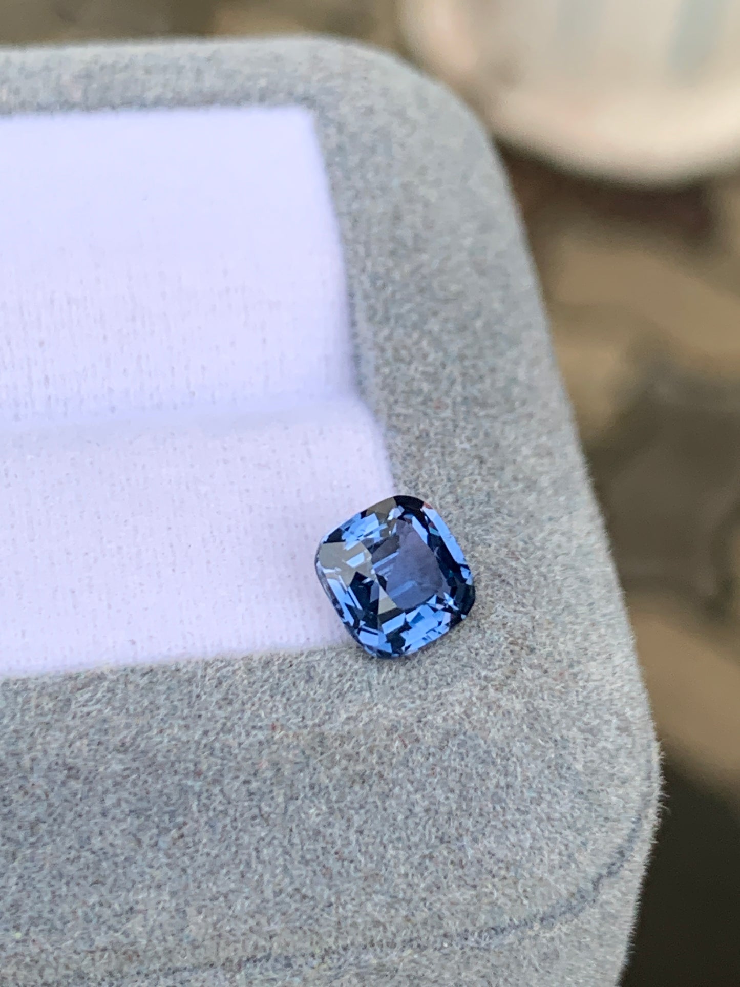 Une gemme rare, le Spinelle bleu • 1,28 ct de Bonnot Paris, est élégamment présenté sur un coffret à bijoux gris clair avec un intérieur blanc, placé en angle.