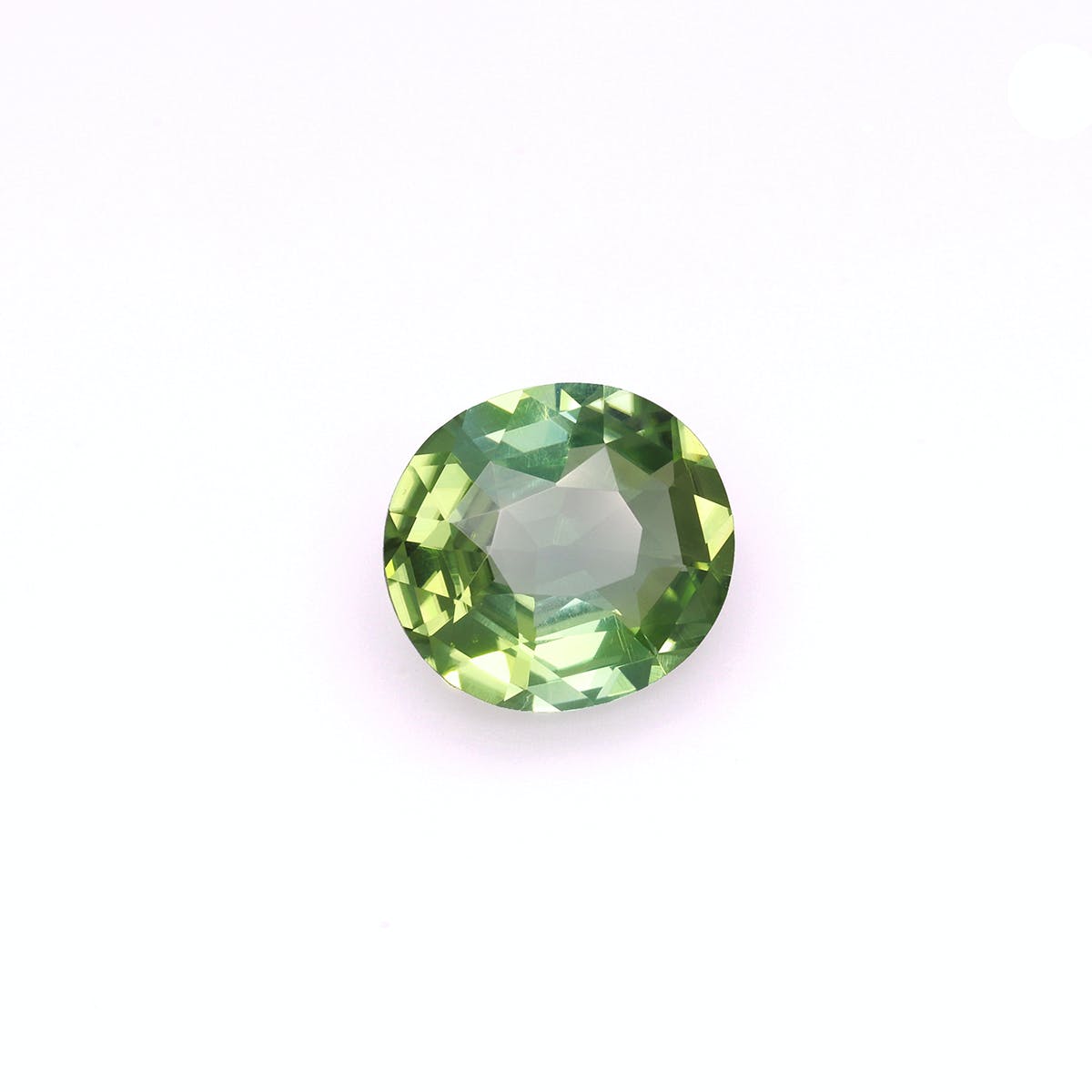 La Tourmaline Verte de Bonnot Paris · 6,17 ct est une pierre précieuse verte ronde et facettée, présentée sur un fond blanc uni et révélant diverses nuances de vert lorsqu'elle capte la lumière.