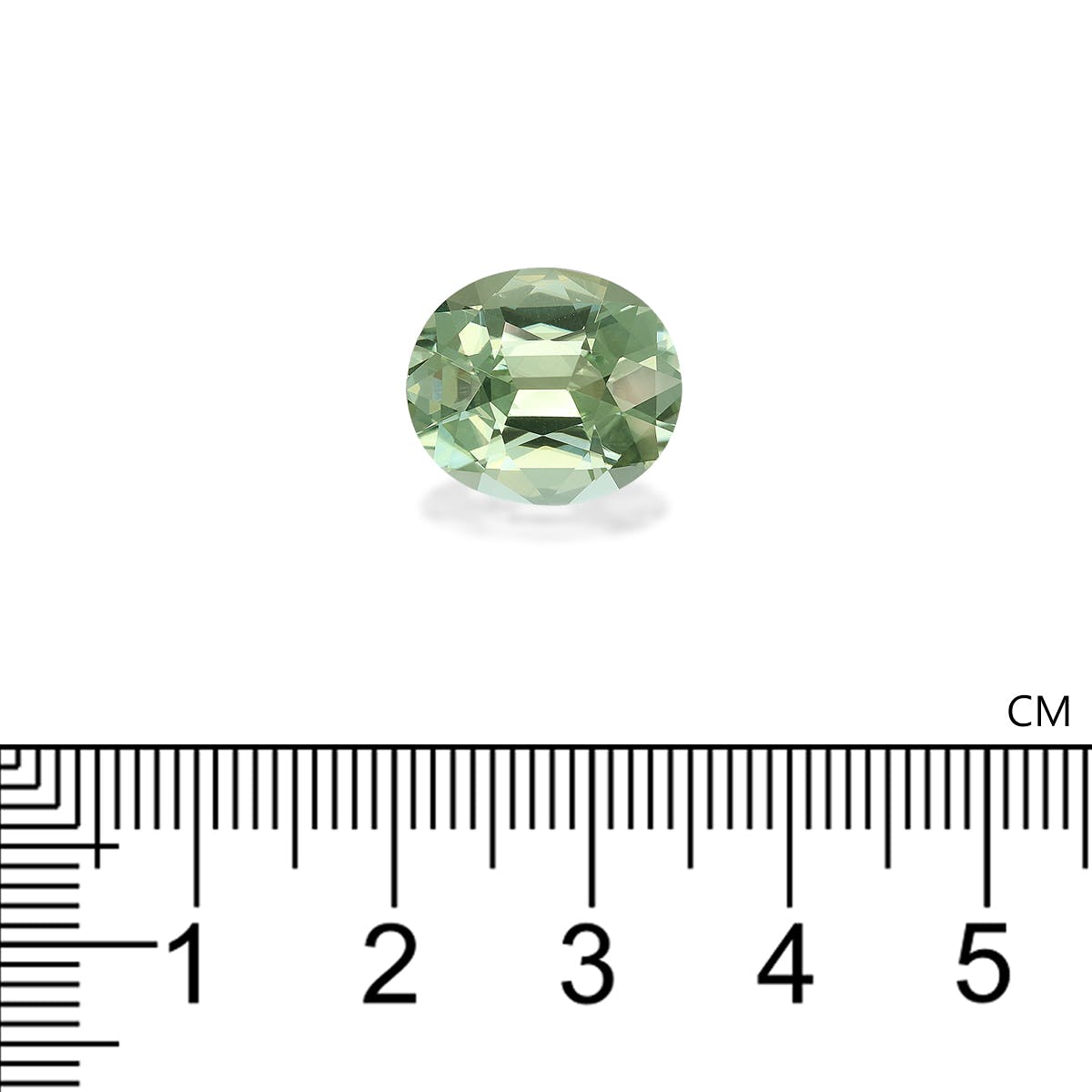 Une Tourmaline Verte ovale vert clair (7,3 ct) de Bonnot Paris est présentée au-dessus d'une règle centimétrique pour l'échelle, sa taille facettée reflétant la lumière et révélant diverses nuances vertes.