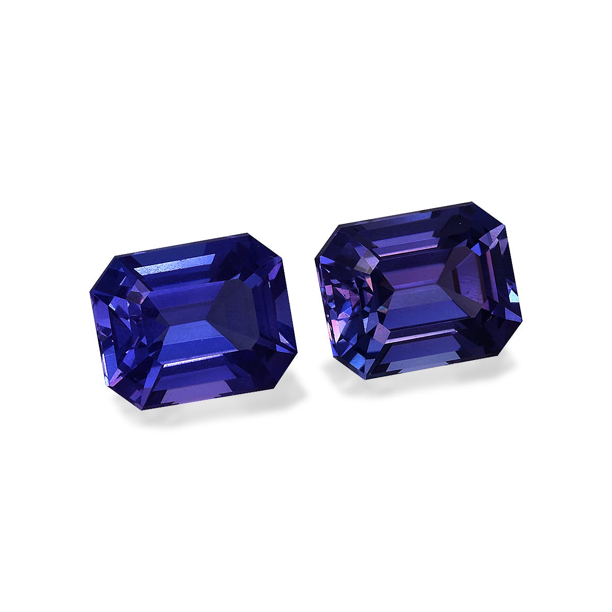 Deux tanzanites taille émeraude de Bonnot Paris, totalisant 6,9 carats, sont placées côte à côte sur un fond blanc uni, mettant en valeur leurs teintes bleu profond et leurs surfaces réfléchissantes.