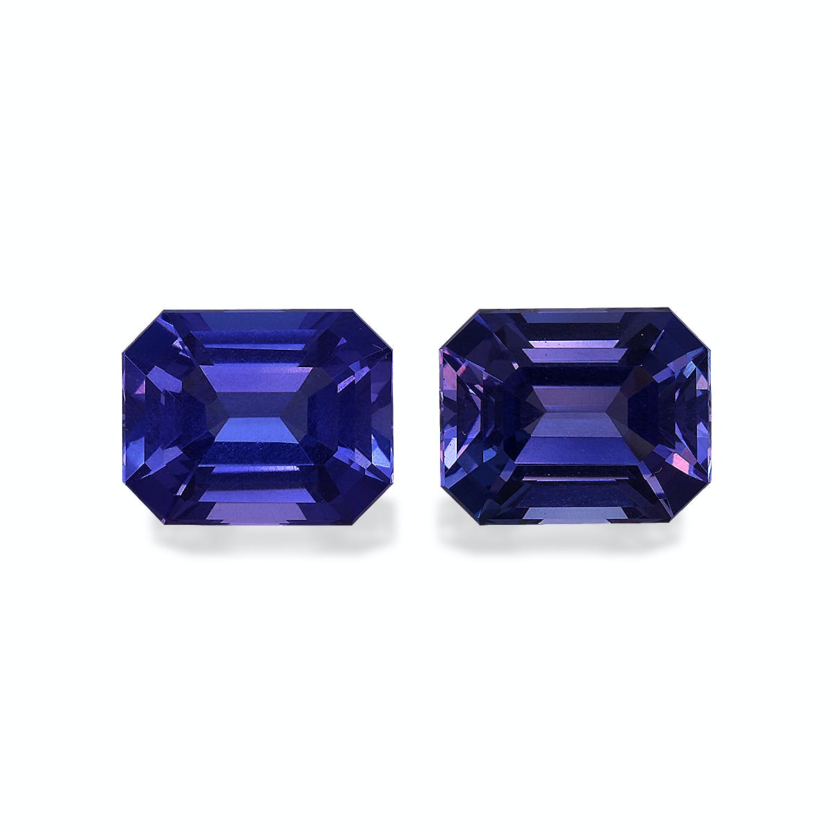 Deux tanzanites Bonnot Paris rectangulaires et facettées (6,9 carats), aux nuances violettes profondes, sont mises en valeur sur un fond uni. Leurs surfaces réfléchissantes mettent en valeur des coupes complexes et des couleurs éclatantes.