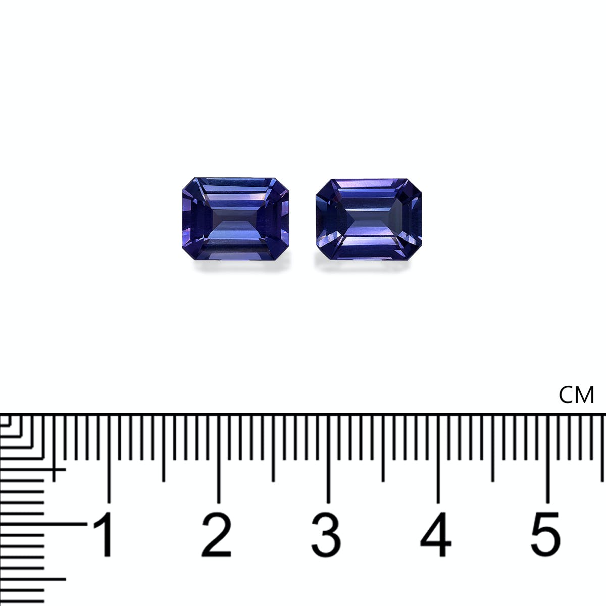 Deux pierres précieuses Tanzanite bleu foncé rectangulaires, chacune d'environ 0,9 cm de long et totalisant 5,82 ct, de Bonnot Paris, sont placées côte à côte au-dessus d'une échelle de mesure en centimètres.