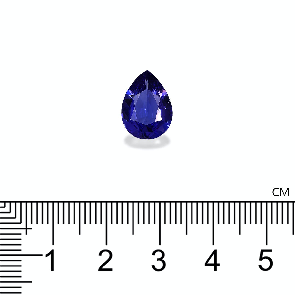 Une tanzanite Bonnot Paris en forme de poire de 3,56 ct, d'un bleu profond et mesurant environ 1,5 cm, est présentée au-dessus d'une règle. Elle projette une ombre sur la surface blanche, contrastant avec le fond sobre.