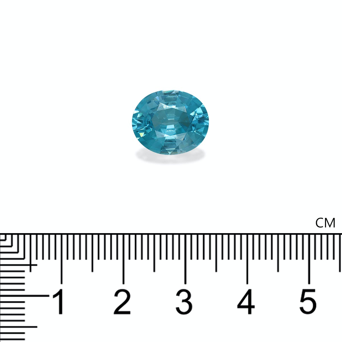 La pierre précieuse Zircon Bleu de 7,65 carats de Bonnot Paris, une gemme bleue ovale mesurant environ 1,8 cm de large, repose sur un fond clair avec des repères de règle en centimètres visibles en dessous.
