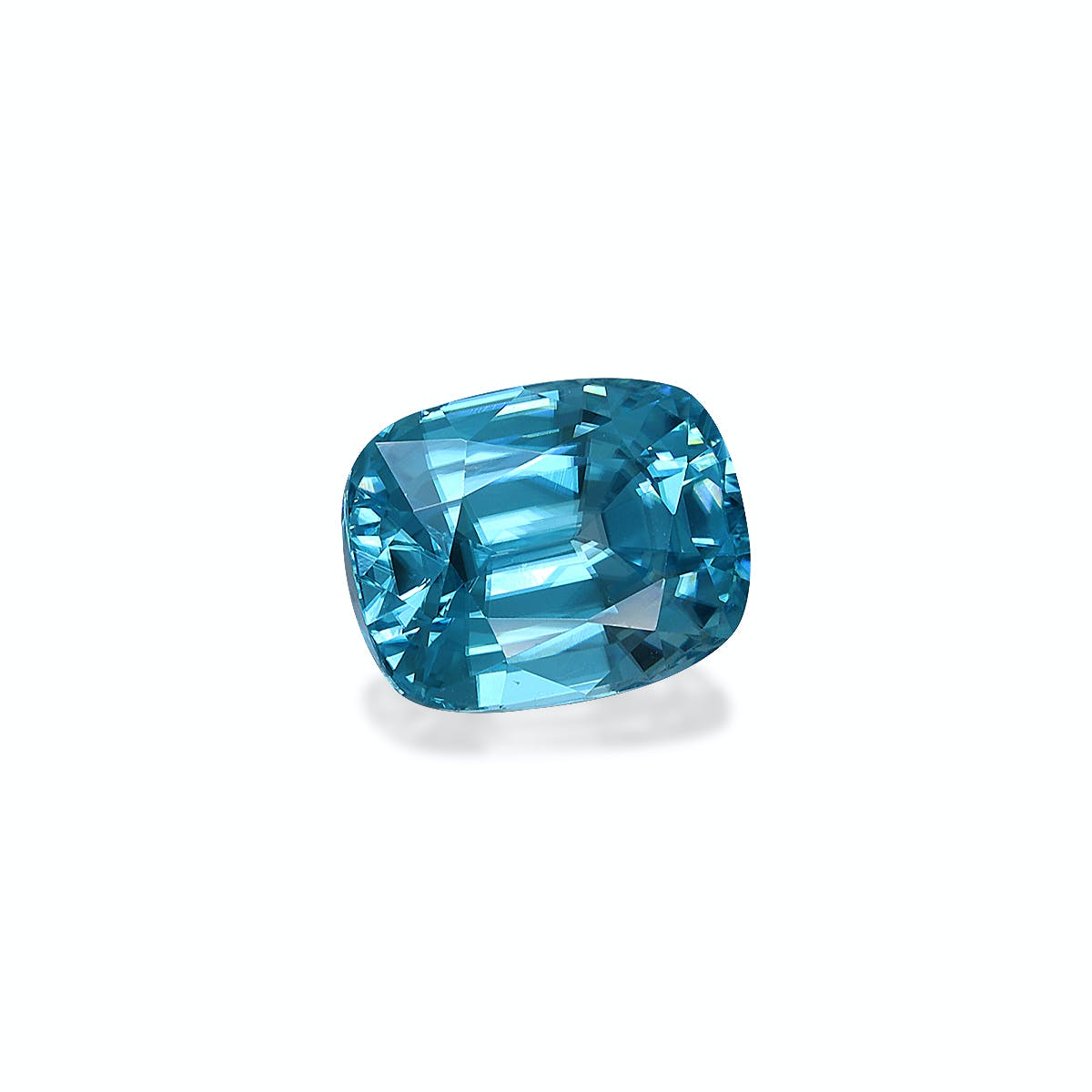 Le Zircon Bleu · 5,29 carats de Bonnot Paris est une pierre précieuse bleue taille coussin à la surface facettée et réfléchissante, sertie sur un fond blanc uni. Ses différentes nuances de bleu lui confèrent profondeur et brillance.