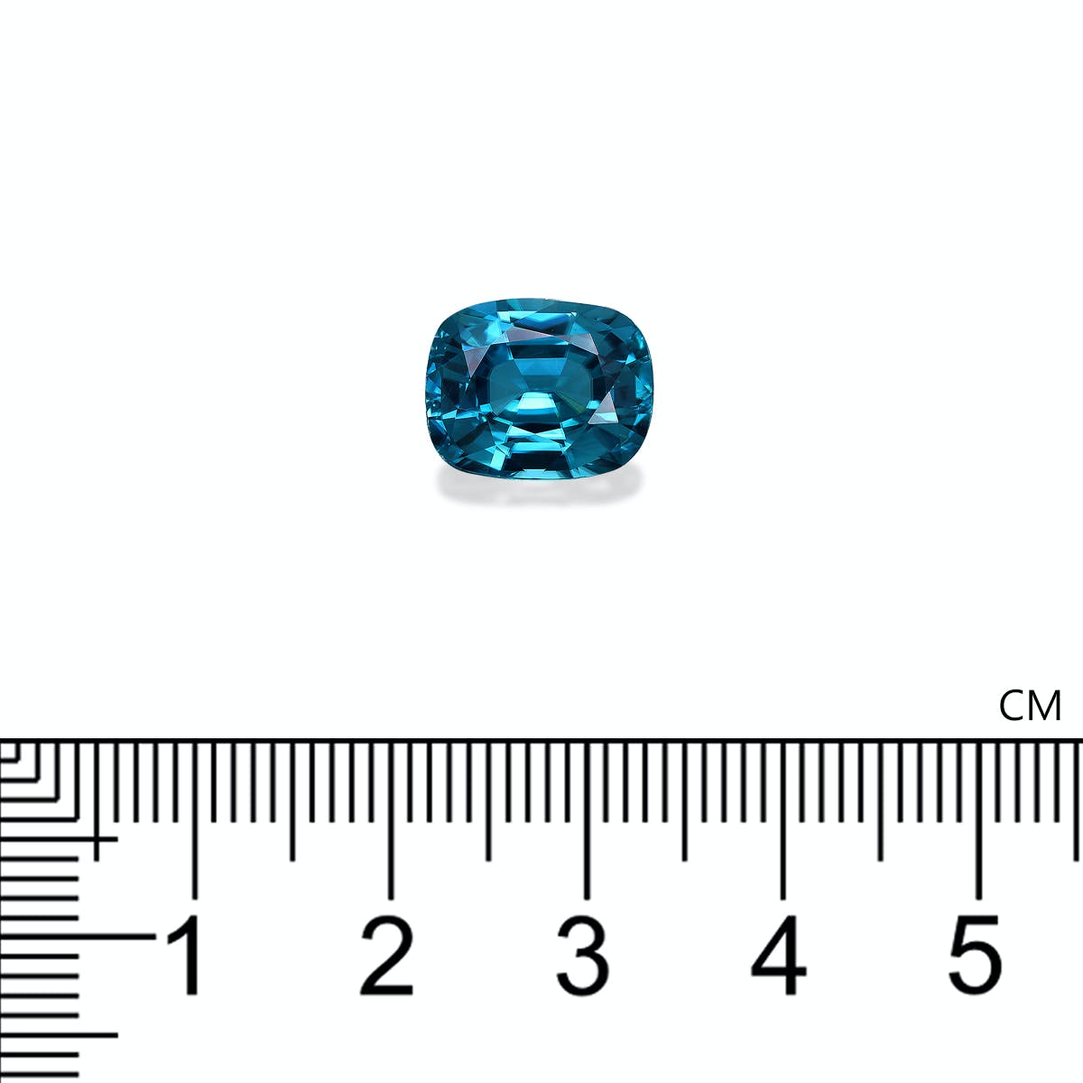 Le Zircon Bleu · 7,58ct de Bonnot Paris, taille coussin, repose sur un fond blanc avec une règle centimétrique en dessous indiquant sa taille à environ 1,2 cm de large.