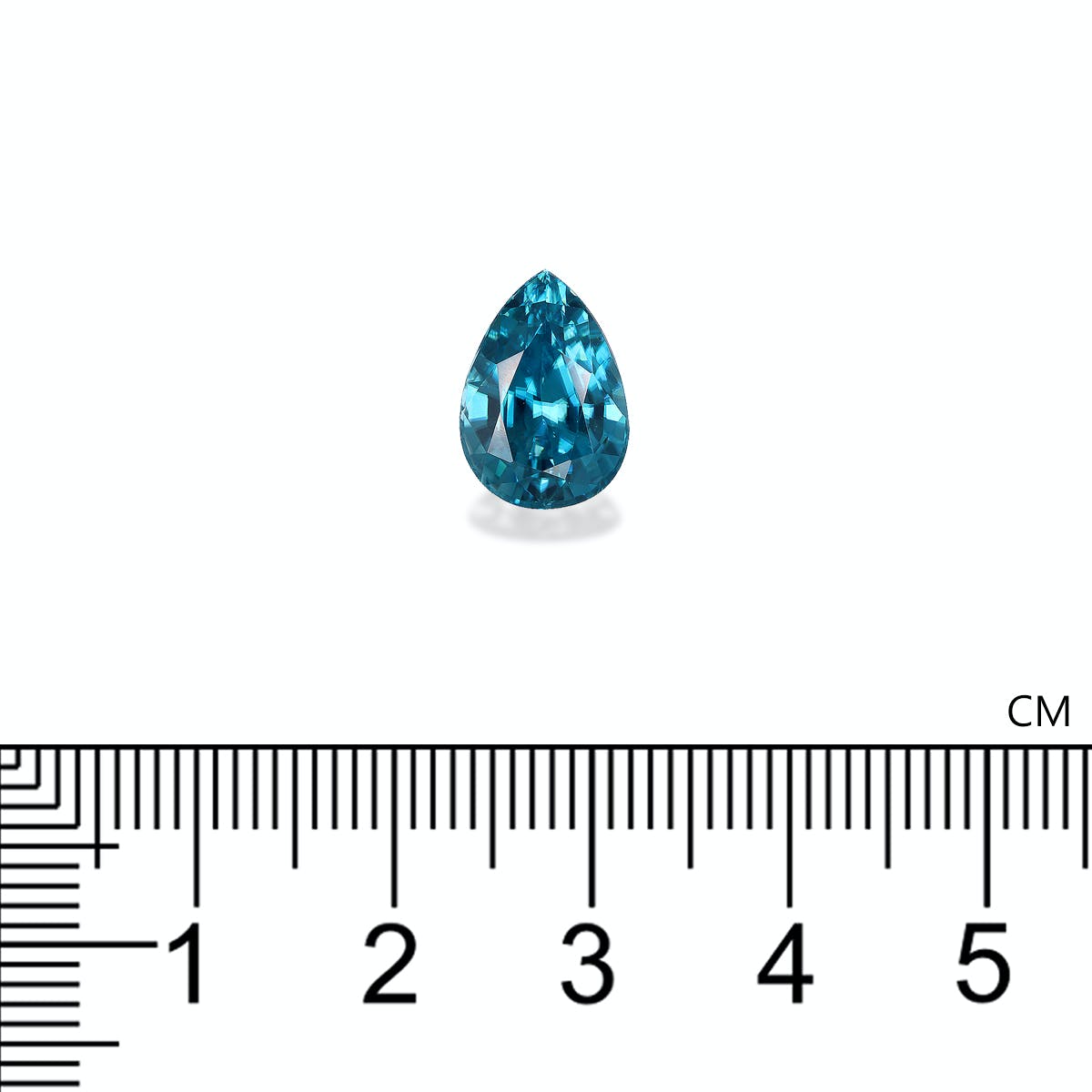 Le Zircon Bleu de Bonnot Paris, une pierre précieuse bleue en forme de larme pesant 6,72 ct, est présenté sur un fond blanc avec une règle en dessous indiquant sa longueur à un peu plus de 1 cm.