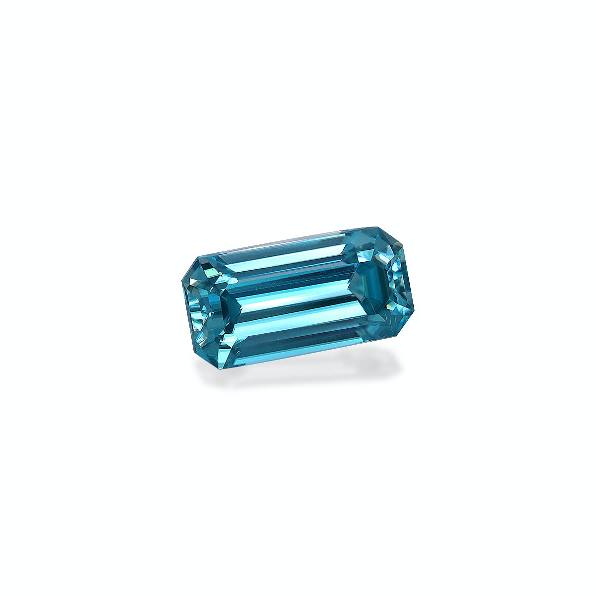 La pierre précieuse Zircon Bleu · 4,75 ct de Bonnot Paris est une pierre bleu profond taille émeraude sertie sur un fond blanc, présentant des facettes réfléchissantes qui mettent en valeur sa clarté et sa brillance.