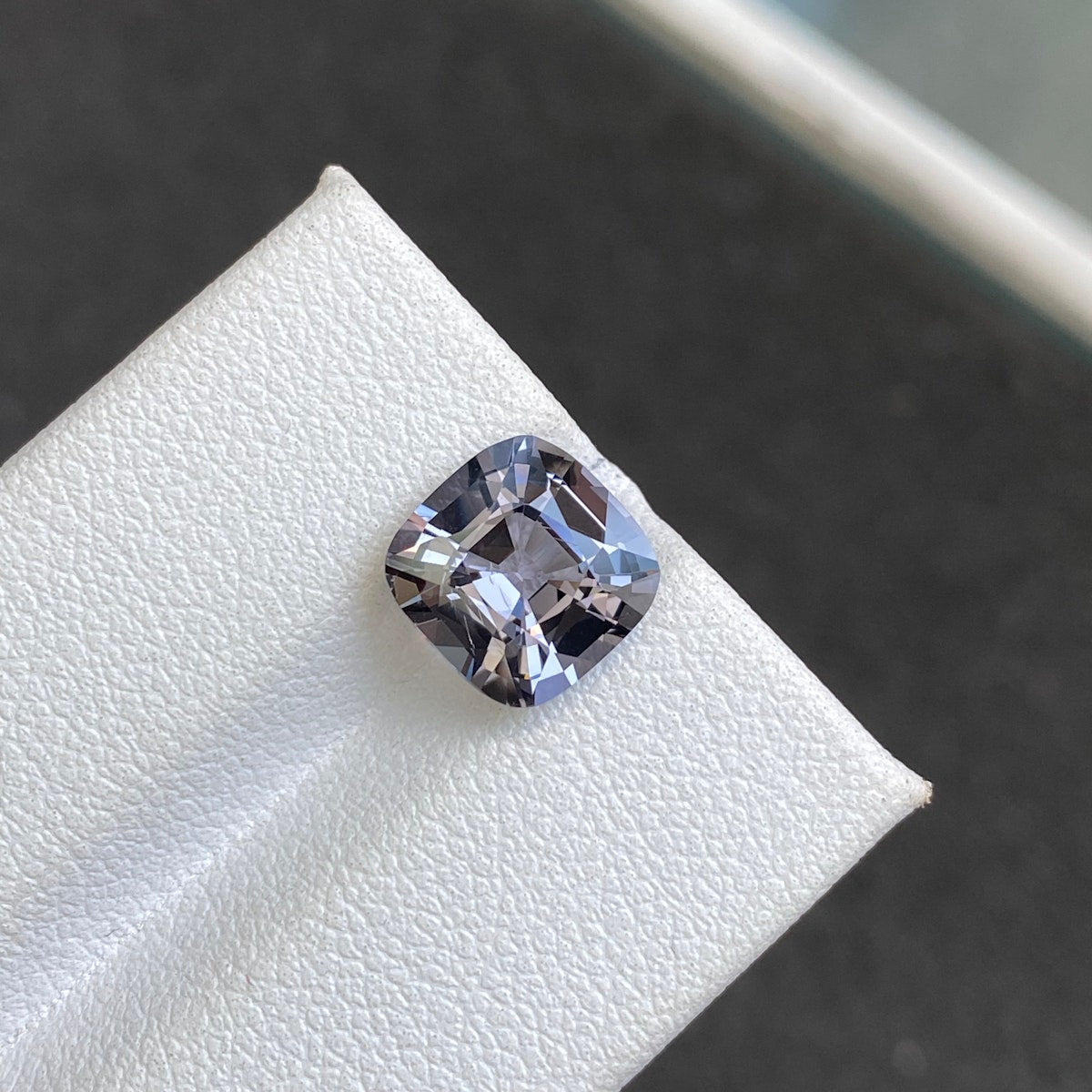 Le Spinelle Gris · 3,31 carats de Bonnot Paris est un diamant taille coussin à surface blanche texturée, scintillant dans des tons gris et argentés. Vu de près, il met en valeur ses facettes et sa clarté sur un fond flou.