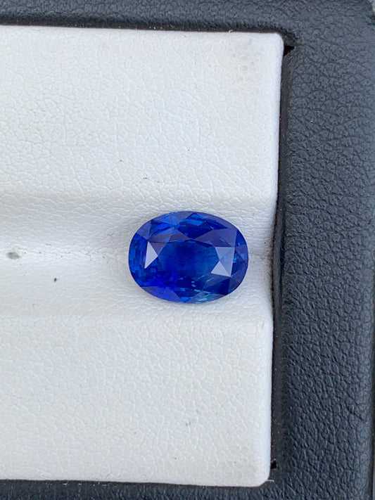 Un Saphir bleu vibrant de 3,59 ct de Bonnot Paris est présenté sur une surface blanche texturée avec une bordure noire, mettant en valeur sa teinte bleu profond et sa clarté grâce à sa taille facettée.