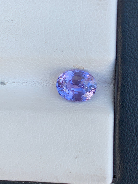 Le Saphir Violet • 1,56ct de Bonnot Paris présente une forme ovale savamment taillée qui scintille sur un fond blanc et noir, avec ses superbes facettes reflétant des notes de rose et de bleu.