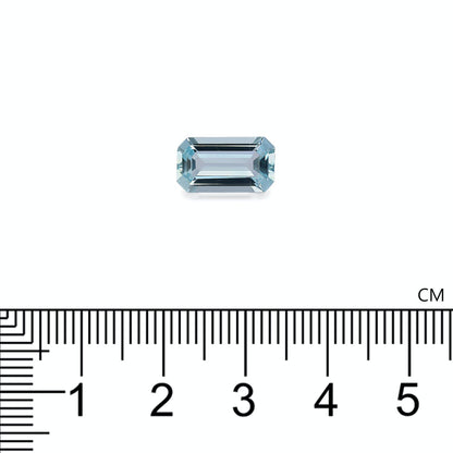 Une petite pierre précieuse rectangulaire Aigue-Marine de 2,73 carats, signée Bonnot Paris, est placée au-dessus d'une règle noire graduée en centimètres. La pierre bleu clair, aux bords taillés avec précision, est centrée sur un fond blanc uni, gradué en millimètres.