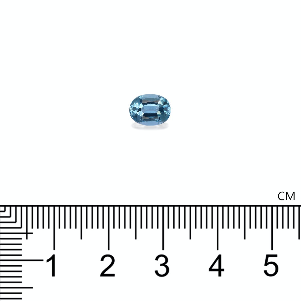 Une petite gemme bleue ovale de Bonnot Paris, ressemblant à une Aigue-Marine de 1,08 ct aux reflets célestes, repose sur une surface blanche. Sous la pierre précieuse se trouve une règle en centimètres, indiquant sa longueur d'environ 0,8 cm.