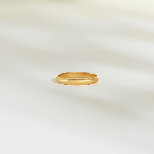 L'Alliance L'Authentique, un simple anneau en or signé Bonnot Paris, repose sur une surface pâle et légèrement éclairée. Les ombres subtiles qui l'entourent créent une atmosphère calme et élégante.