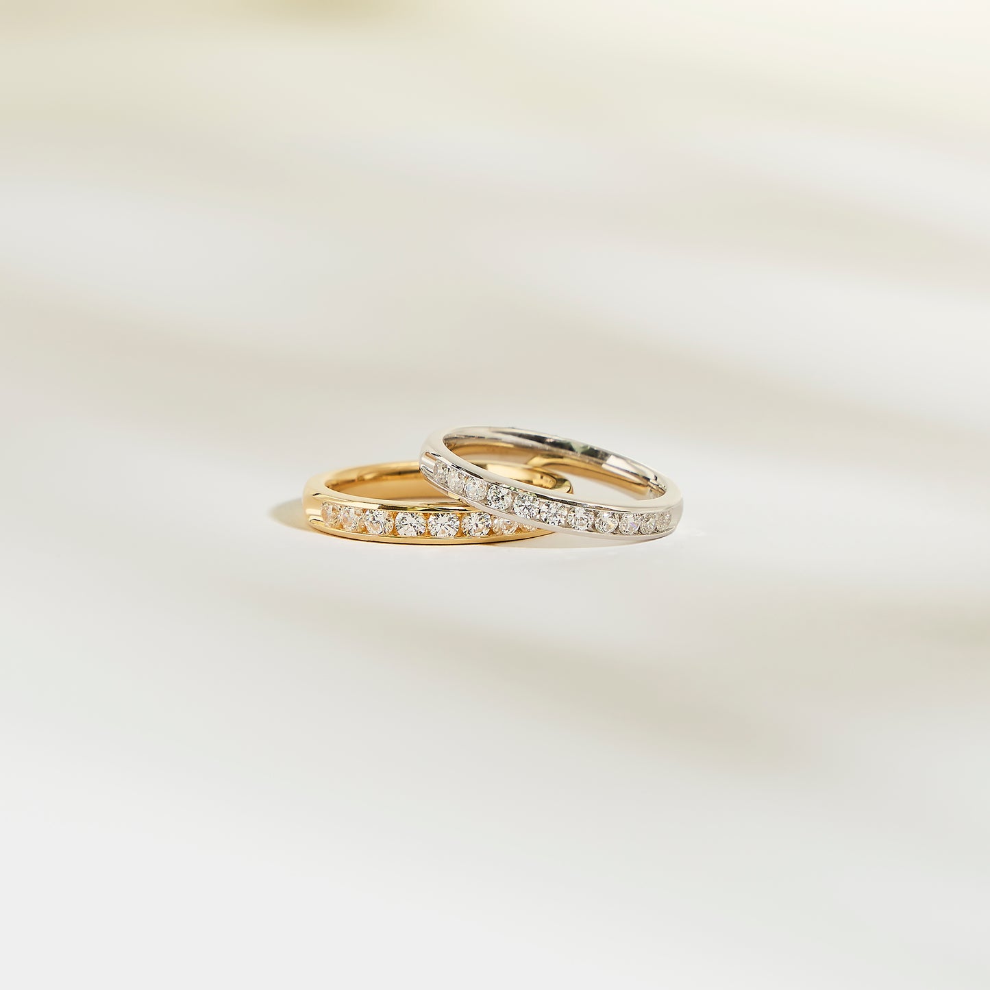 Deux bagues Alliance La Délicate de Bonnot Paris, l'une en or et l'autre en argent, reposent élégamment sur une surface claire. Elles sont toutes deux ornées d'une rangée de petits diamants.