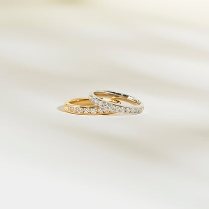 Deux bagues Alliance La Délicate de Bonnot Paris, l'une en or et l'autre en argent, reposent élégamment sur une surface claire. Elles sont toutes deux ornées d'une rangée de petits diamants.