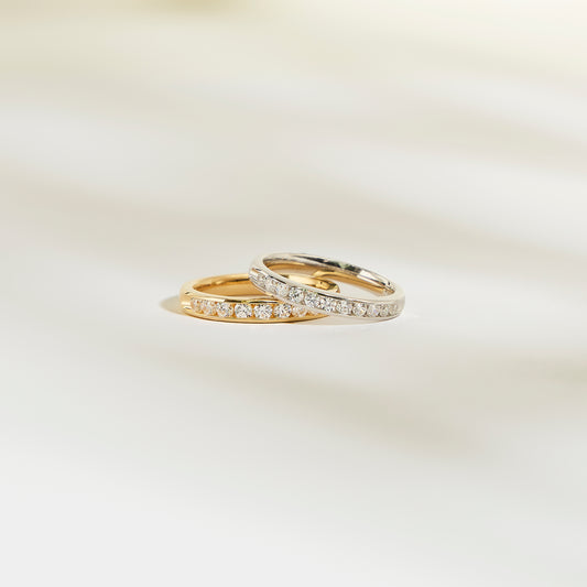 Deux bagues Alliance La Délicate de Bonnot Paris, l'une en or et l'autre en argent, reposent élégamment sur une surface claire. Elles sont toutes deux ornées d'une rangée de petits diamants.