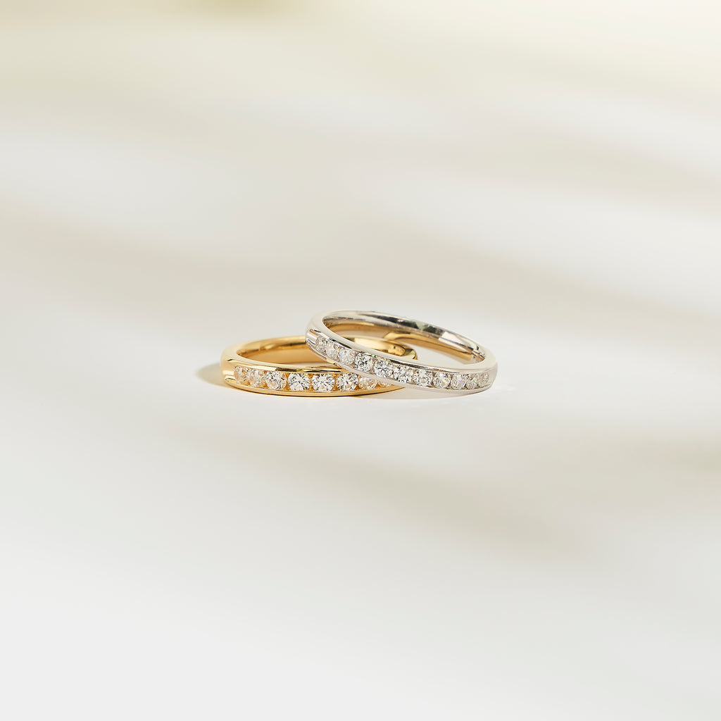 Deux bagues Alliance La Délicate de Bonnot Paris, l'une en or et l'autre en argent, reposent élégamment sur une surface claire. Elles sont toutes deux ornées d'une rangée de petits diamants.