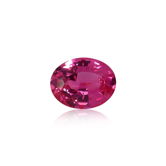 Le Spinelle Mahenge de 1,59 ct de Nascendi Paris est une pierre précieuse rose éclatante de forme ovale présentée sur une surface blanche réfléchissante, mettant en valeur sa teinte vibrante et ses facettes accrocheuses de lumière pour une allure vraiment unique.