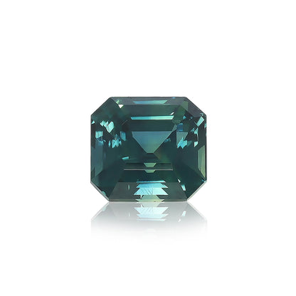 Un diamant taille carrée « Saphir Teal · 3,03 ct » de Bonnot Paris, d'une couleur bleu sarcelle profonde avec des bords biseautés et des facettes réfléchissantes, repose sur une surface blanche projetant une ombre subtile.