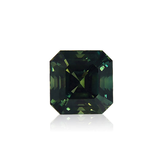 Le Saphir Vert · 6,53ct de Bonnot Paris est une pierre précieuse taille émeraude carrée avec une teinte vert foncé sur fond blanc, dotée de facettes réfléchissantes qui créent des nuances vibrantes de vert et de bleu.