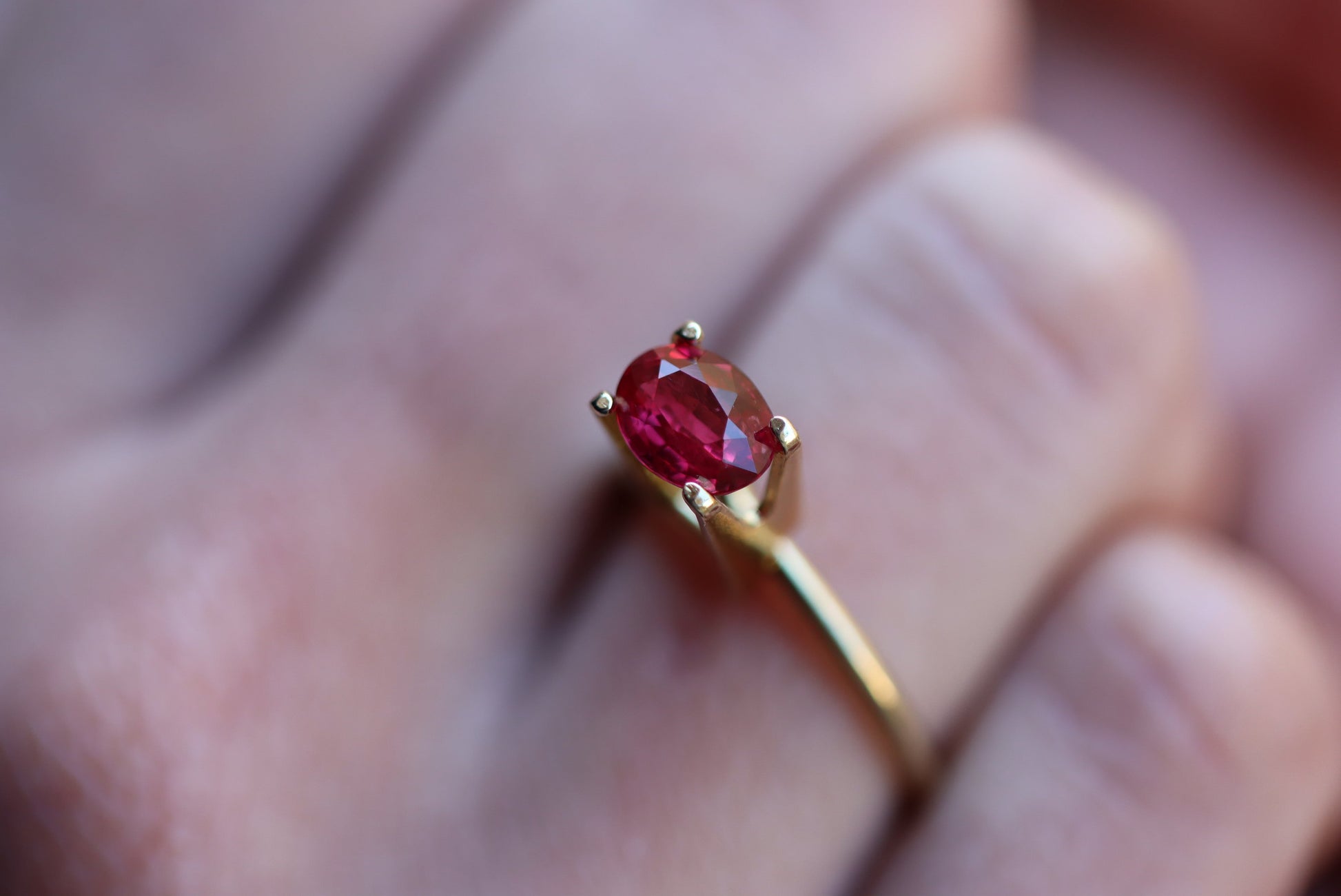 Gros plan d'une main portant la bague en or « Rubis du Mozambique · 1,52 ct » de Bonnot Paris, ornée d'une pierre rouge ovale. L'arrière-plan flou met en valeur la couleur vive et l'éclat de la pierre.