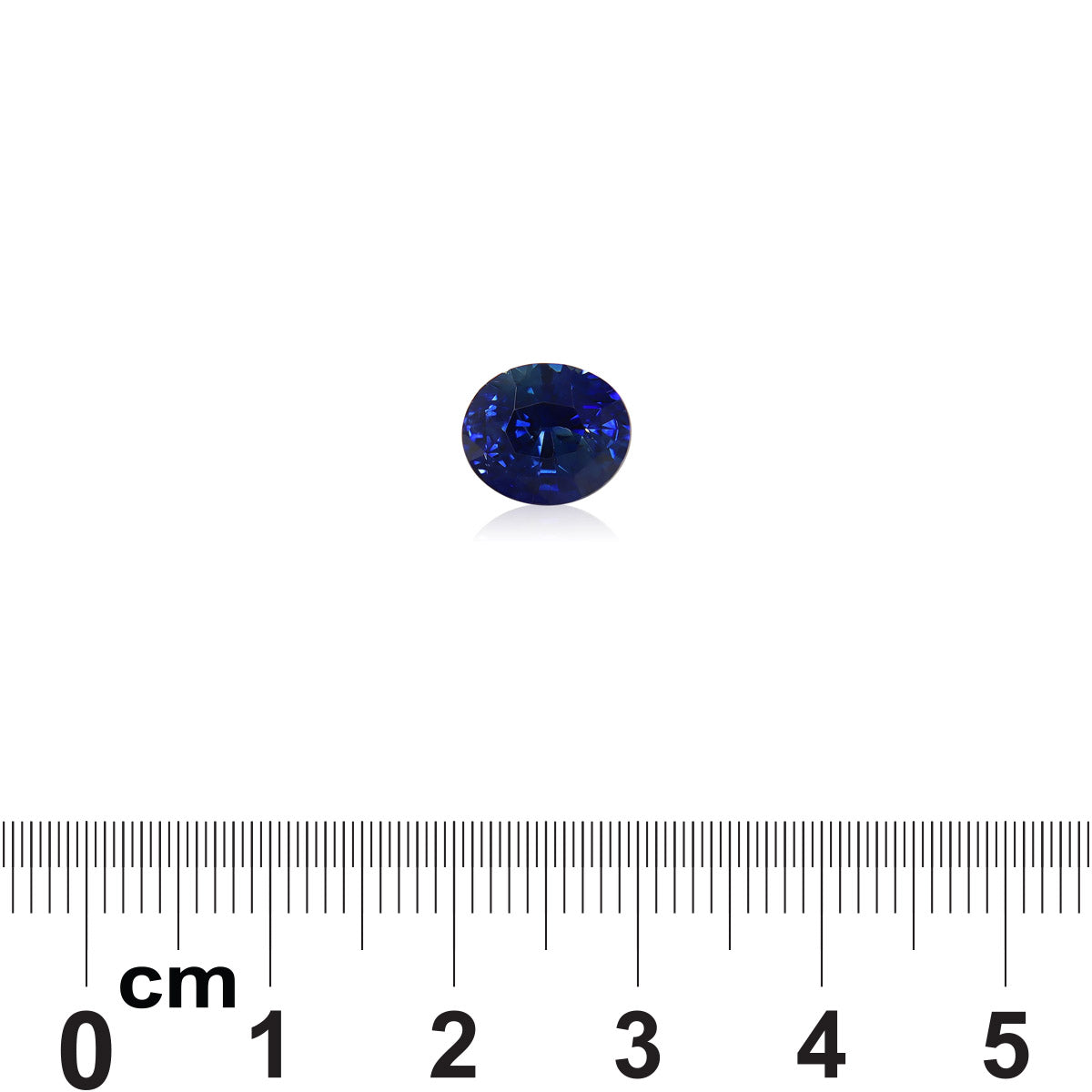 Le Saphir Bleu, un saphir bleu ovale de 3,52 carats de Bonnot Paris, est présenté sur un fond blanc à côté d'une règle en centimètres pour indiquer sa taille.
