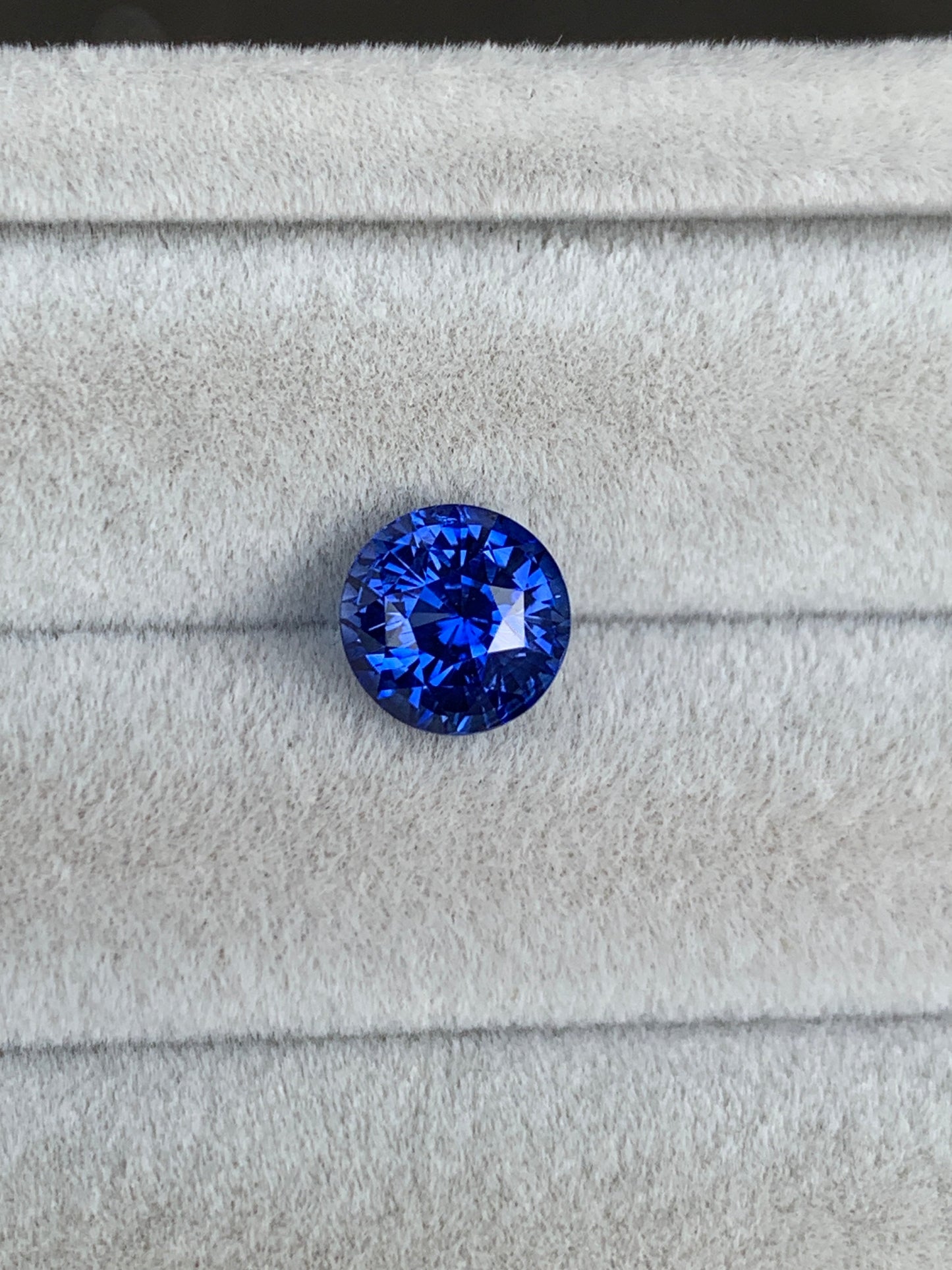 Un Saphir Bleu rond taille brillant • 2,52ct de Bonnot Paris repose sur un tissu doux et gris clair, accentuant sa couleur vive et son éclat.