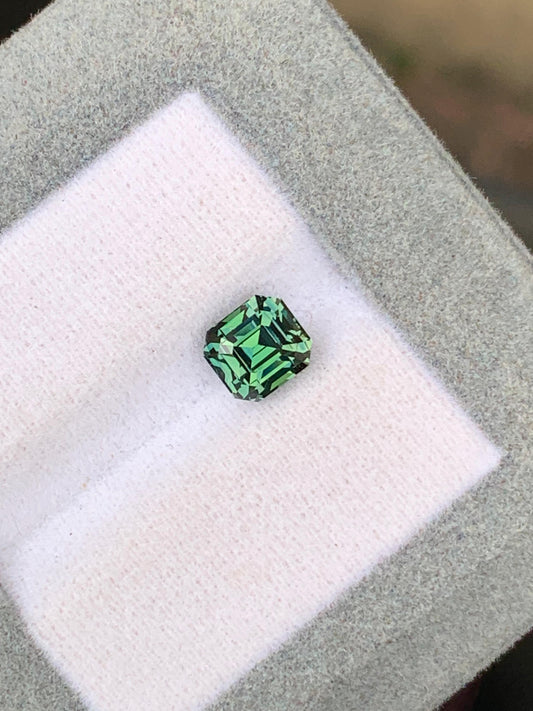Le Saphir Teal • 2,07 ct, une pierre précieuse verte taille émeraude de Madagascar par [NOUVEAU] Bonnot Paris, est présenté dans un coffret coussiné gris et blanc.