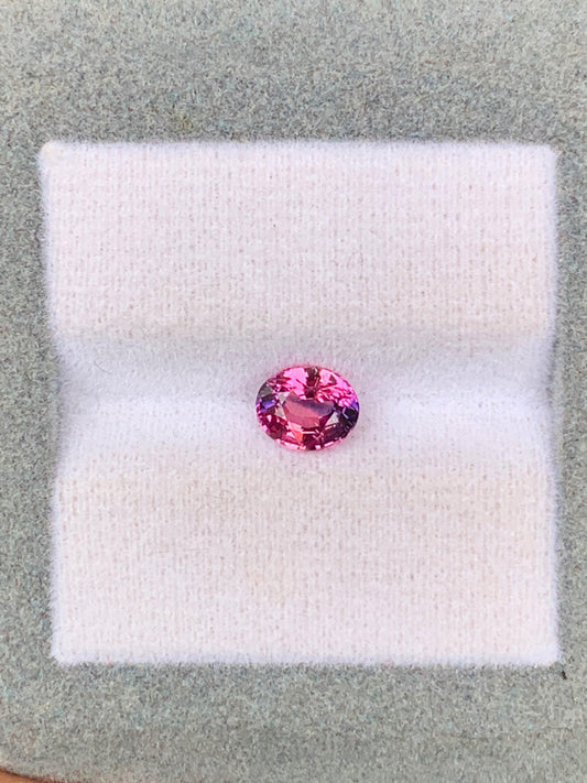 Un Saphir bicolore de 1,06 ct du Sri Lanka, par Bonnot Paris, est présenté sur un tissu blanc doux avec un cadre gris, apparaissant vibrant et réfléchissant.