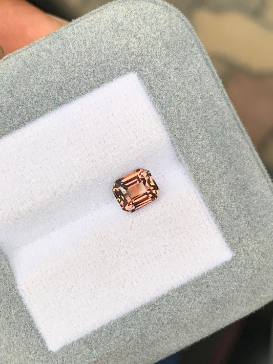 Le Saphir bicolore • 1,68ct de [NOUVEAU] Bonnot Paris, une pierre précieuse rose étincelante avec une taille émeraude, rappelle les teintes vibrantes du Sri Lanka et est niché dans un doux coffret à bijoux en velours gris.