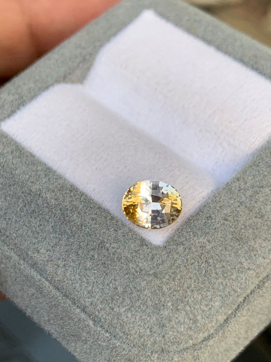 Un Saphir bicolore de 1,75 carat de Bonnot Paris, provenant du Sri Lanka, est présenté dans un écrin blanc et gris avec un intérieur en tissu blanc doux.
