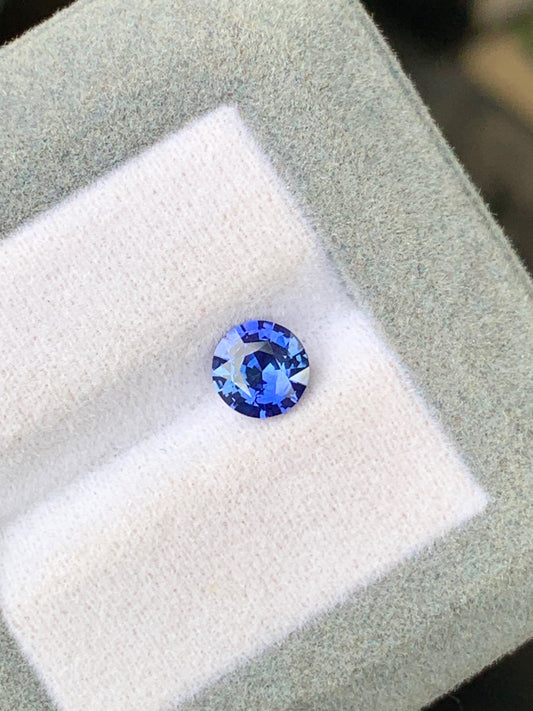 Le Saphir bleu de 1,10 ct de Bonnot Paris, un saphir naturel du Sri Lanka, est serti sur un coussin blanc doux bordé de gris. Sous la lumière, sa forme ronde scintille, mettant en valeur ses facettes et sa riche couleur bleue.
