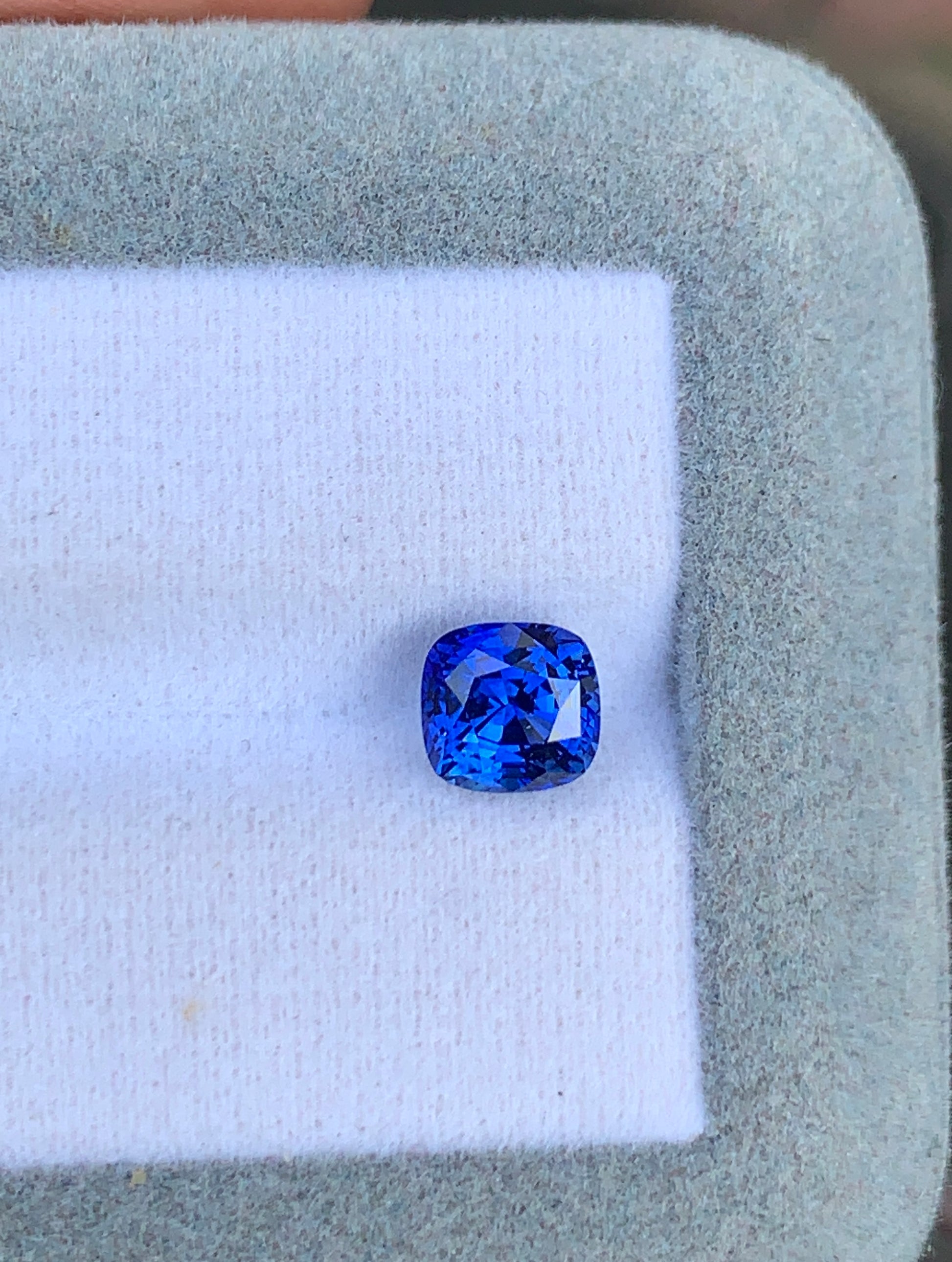 Un Saphir bleu vibrant de 2,20 ct de Bonnot Paris est élégamment présenté sur un coussin blanc à l'intérieur d'un écrin à bijoux gris.
