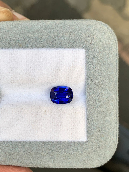 Le Saphir bleu • 2,50 carats de Bonnot Paris, serti sur un tissu blanc dans un écrin gris, met en valeur sa couleur intense et sa taille coussin. Cette pierre rare incarne parfaitement le charme d'une pierre précieuse.