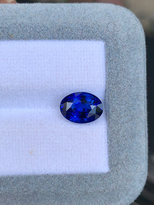 Le Bonnot Paris Saphir bleu 4,02ct, une gemme ovale bleu profond du Sri Lanka, est élégamment mis en valeur sur une surface matelassée blanche et grise.