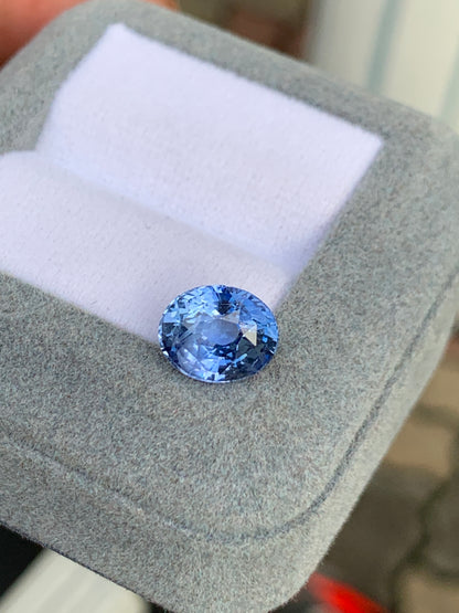 Gros plan sur la pierre précieuse Saphir bleu • 4,02ct de Bonnot Paris, scintillante dans un écrin gris à l'intérieur blanc, sur un fond légèrement flou.